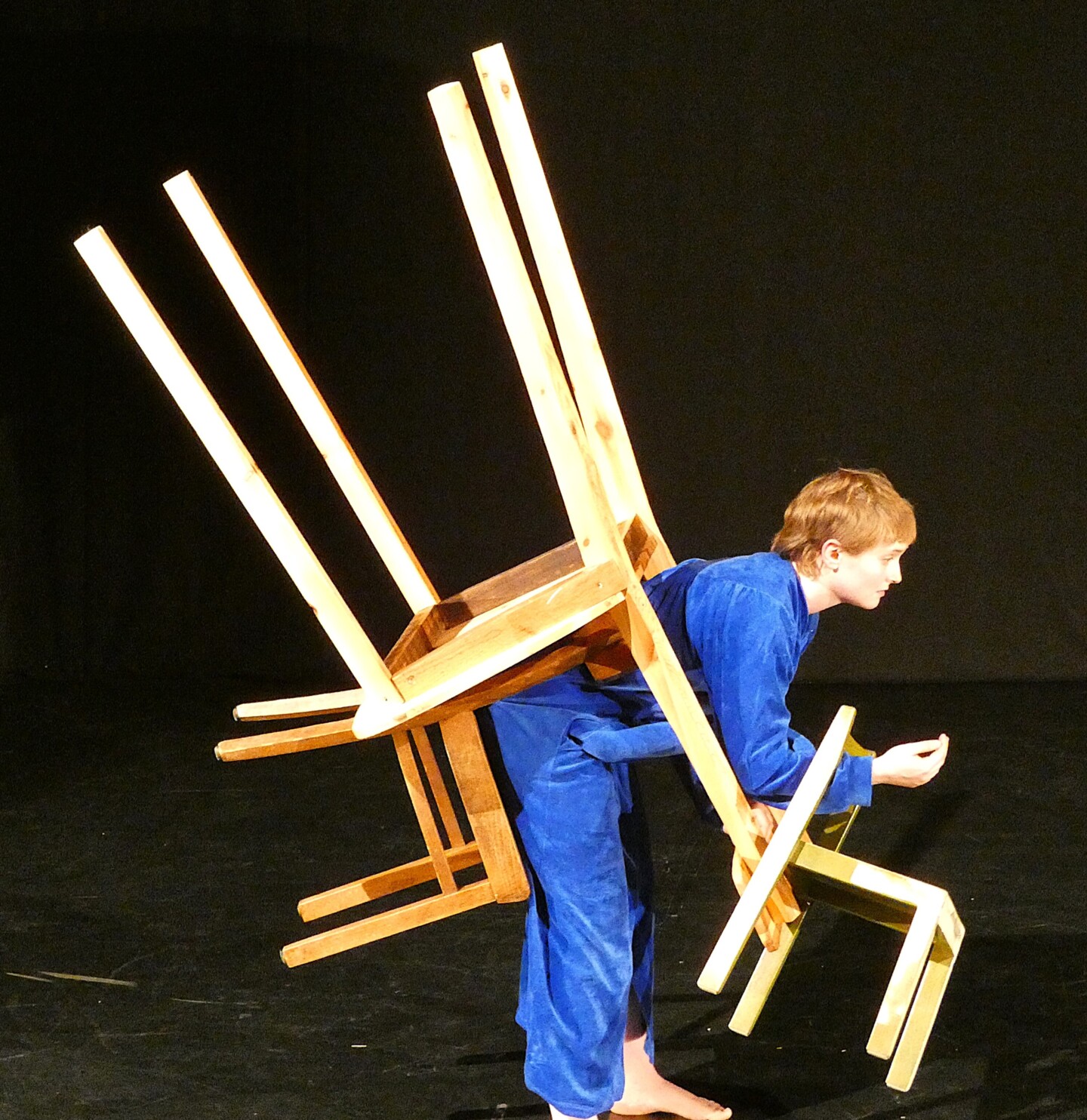 Eine junge Frau ist in mehreren kleinen und großen Stühlen verheddert