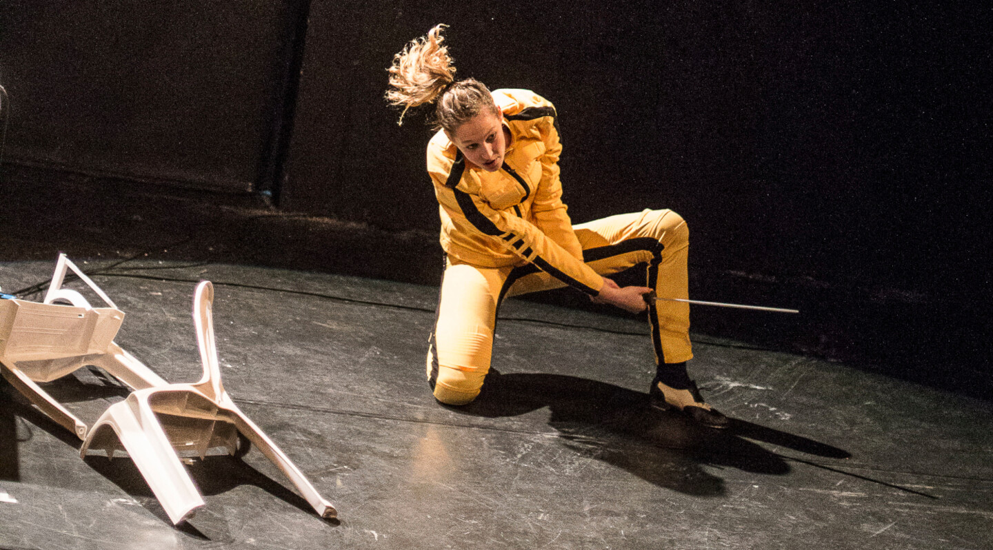  – Eine Frau mit einem Samuraischwert, daneben ein zerteilter Plastikstuhl